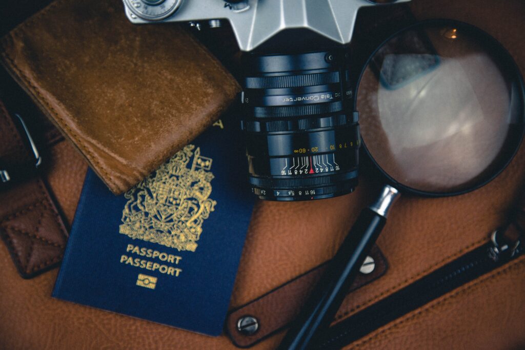 Wallet, Canadian passport, camera lens and magnifying glass on top of a knapsack